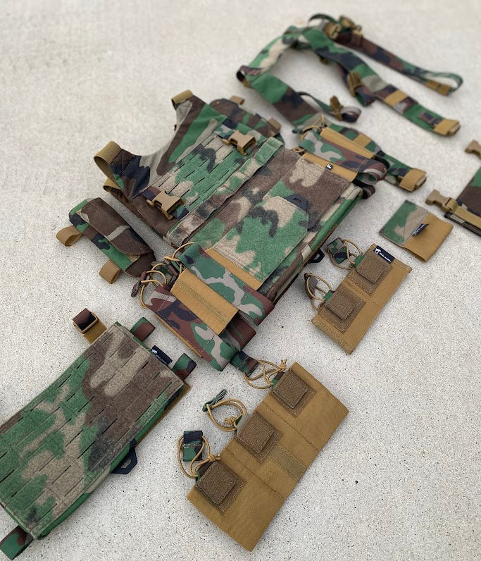 Camouflage tactical vest with multiple pouches on a light gray background