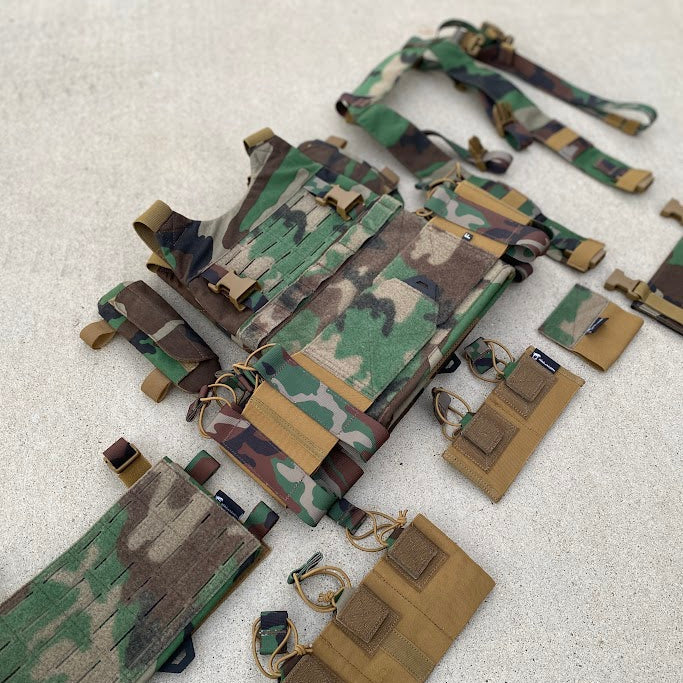 Camouflage tactical vest with multiple pouches on a light gray background